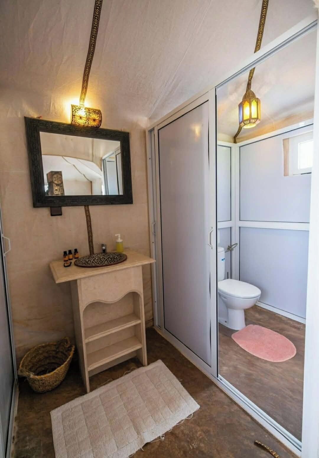 A bathroom with a mirror, sink, toilet, and shower area.