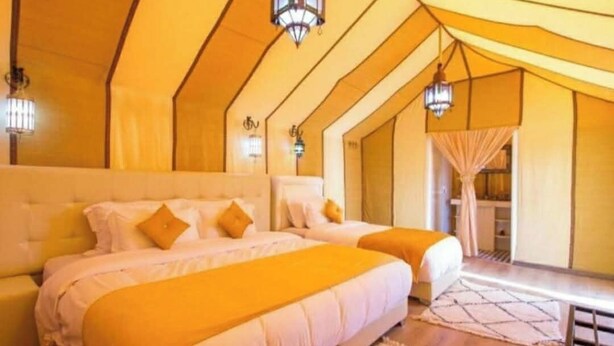 Une chambre avec deux lits, une grande fenêtre et une vue sur l’extérieur.