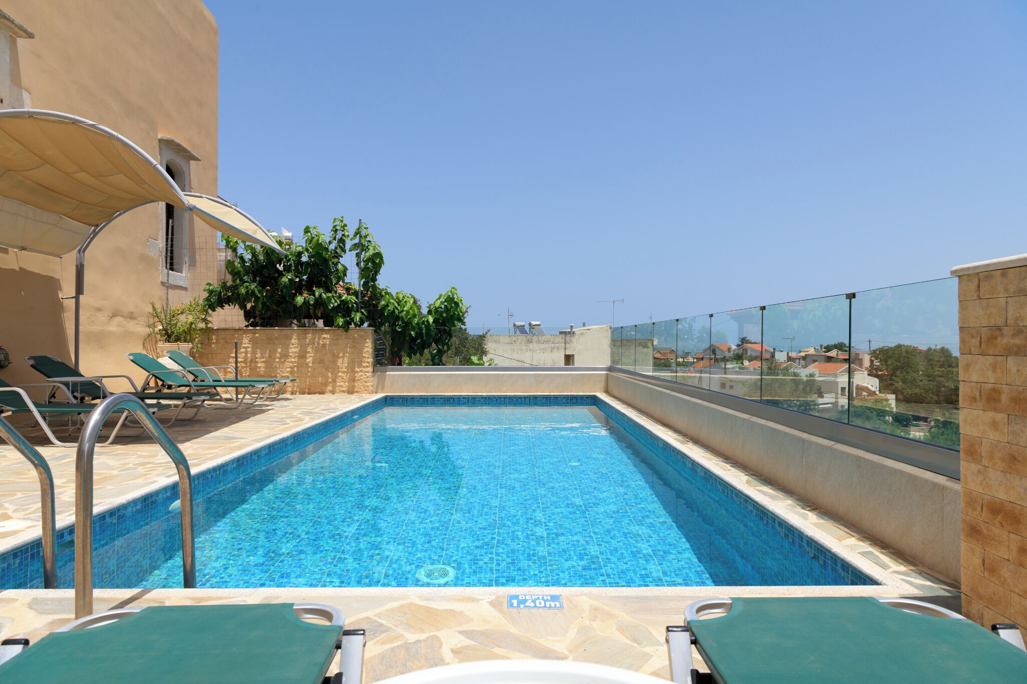 Ein Dachpool mit klarem, blauem Wasser, umgeben von Liegestühlen und einer Glasumrandung.