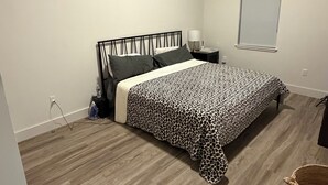 Makuuhuone, jossa on sänky, yöpöytä, lamppu ja ikkuna.