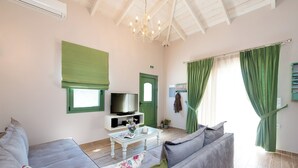 Ein Wohnzimmer mit einer Couch, einem Couchtisch, einem Fernseher und einer grünen Tür.