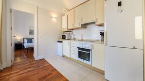 Eine moderne Küche mit weißen Schränken, einem Backofen, einer Mikrowelle und einem Kühlschrank.