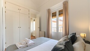 Ein Hotelzimmer mit Bett, Nachttisch mit Lampe, einem Fenster mit Vorhängen und einem Schrank.