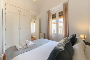 A hotel room with a bed, a nightstand with a lamp, a window with curtains, and a wardrobe. - M (TOL241) Spectacular 2 bedroom apartment in the Plaza Mayor (Madrid)