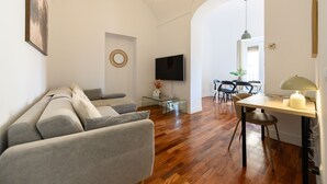 Ein modernes Wohnzimmer mit einer Couch, einem Esstisch und einem Fernseher.