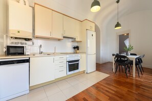 A modern kitchen with white cabinets, a built-in oven, a microwave, and a dishwasher. There is a dining area with a table and chairs. - M (TOL241) Spectacular 2 bedroom apartment in the Plaza Mayor (Madrid)