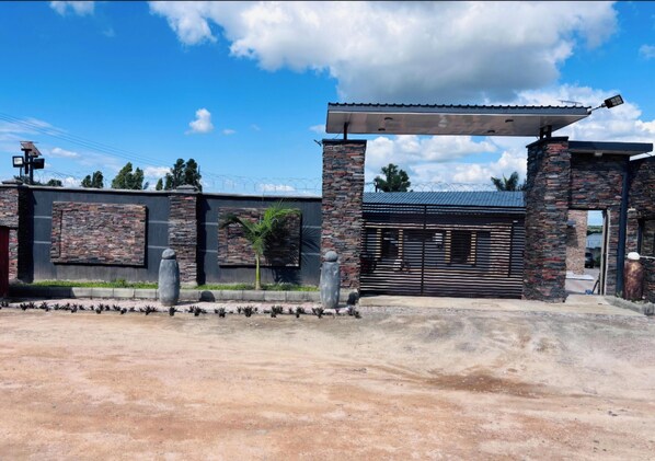 A gated entrance with a stone and metal gate, a covered walkway, and a clear sky.