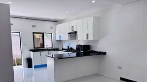 Een moderne keuken met witte kastjes, een zwart aanrecht en een roestvrijstalen fornuis.