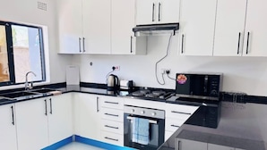 Een moderne keuken met witte kastjes, een zwart aanrecht en een fornuis.