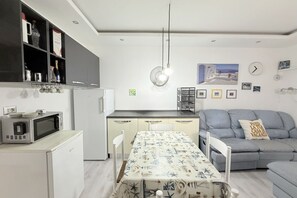 Un espacio habitable compacto con kitchenette, comedor y sofá.