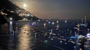 Una marina costera de noche con barcos amarrados y un muelle que se adentra en el agua.