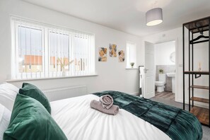 A bedroom with a bed, a window, a radiator, and a bathroom visible through an open door. - 59 Eagle Drive (Grimsby)