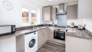 A compact kitchen with a washing machine, a stove, and a sink. - 59 Eagle Drive (Grimsby)