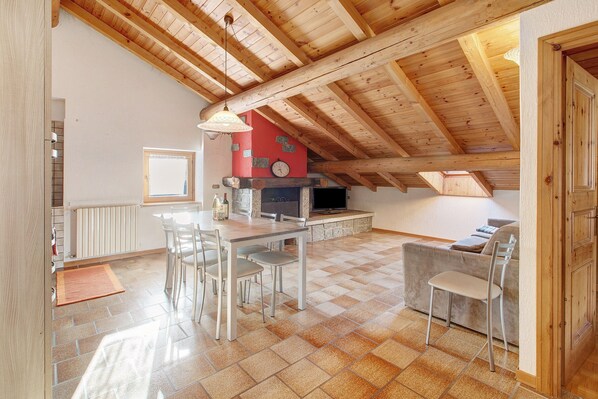 A spacious kitchen with a dining area, wooden ceiling beams, and a stone fireplace. - Apartment '4' with Mountain View, Shared Garden and Wi-Fi (Isolaccia)