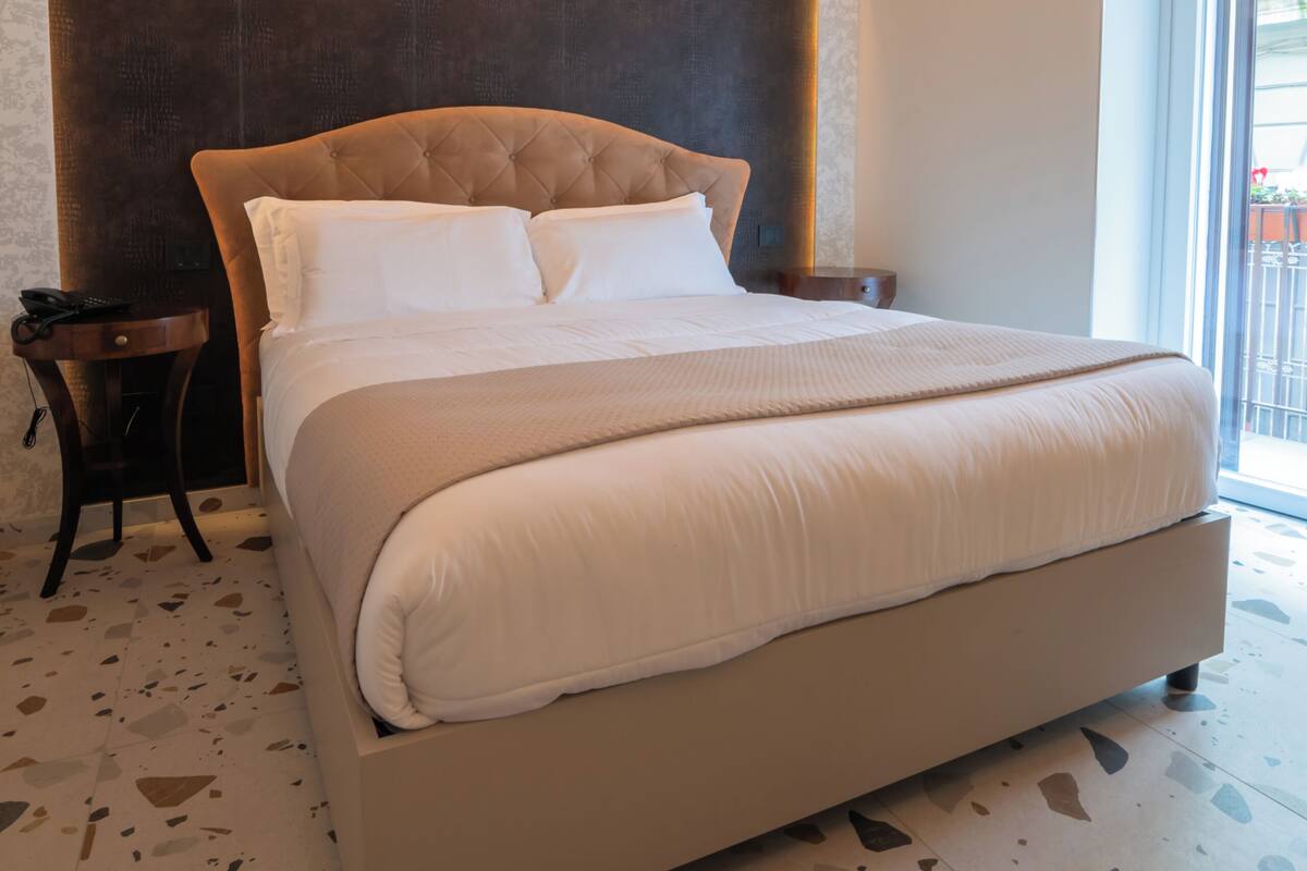 Une chambre à coucher avec un grand lit, une tête de lit, une table de chevet et une fenêtre donnant sur un beau paysage.