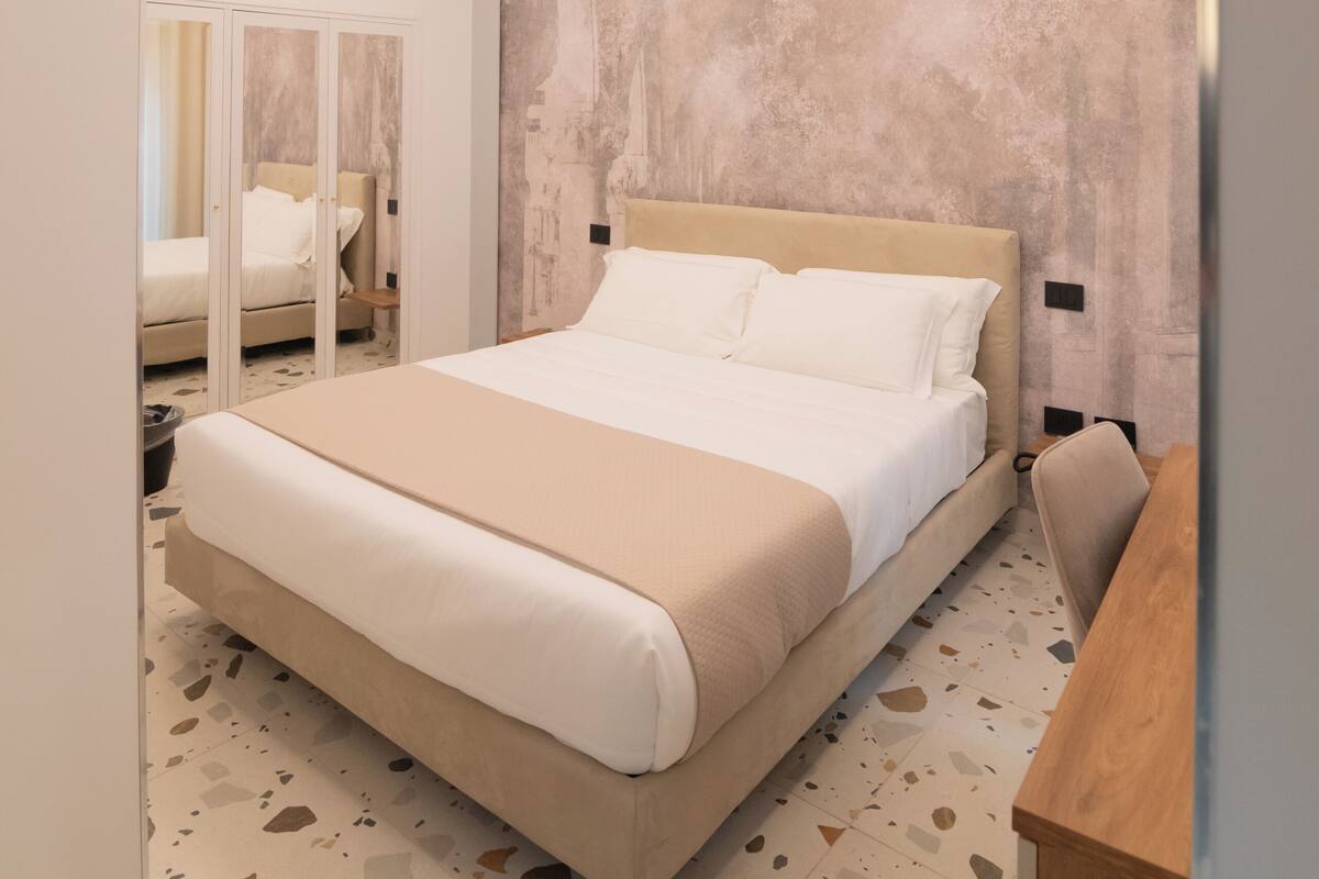 Une chambre à coucher moderne avec un grand lit, un placard avec des portes miroir et un luminaire au plafond au design original.