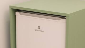 A compact, green-framed appliance, likely an air conditioner, with a white interior, placed against a wall with a speckled floor.