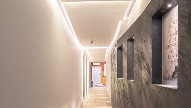 Een moderne hal met een marmeren wand, inbouwverlichting en een patroon vloer.
