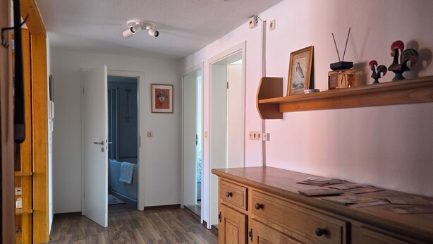A hallway with wooden flooring, a wooden cabinet with drawers, a ceiling-mounted light fixture, and a door leading to another room. - "Saskia" Vacation Rental with a Beautiful View of the Old Town and a Rooftop Terrace! (Hammelburg)