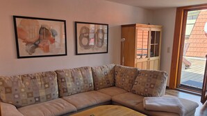 A living room with a sofa, a coffee table with magazines, and a wooden cabinet. - "Saskia" Vacation Rental with a Beautiful View of the Old Town and a Rooftop Terrace! (Hammelburg)