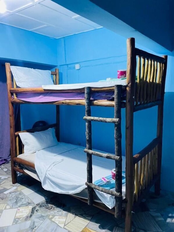 A bunk bed with a ladder, a small table with a pink object, and a blue wall. - Bush Beach backpackers (Vilanculos)