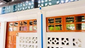 Un edificio con tetto in metallo, porte in legno e un muro bianco decorato con intagli.
