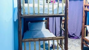 Un letto a castello con struttura in legno e biancheria bianca in una stanza dalle pareti azzurre e pavimento piastrellato.