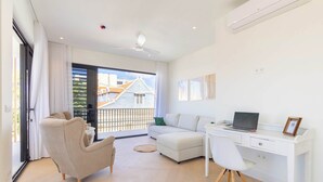 A modern living room with a sofa, a desk, and a laptop. There is a balcony with a view of buildings. - Home Pietermaai in Willemstad (Willemstad)