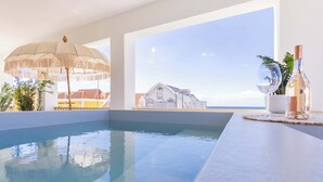 An indoor swimming pool with a view of a building and a bottle of wine on a table. - Home Pietermaai in Willemstad (Willemstad)