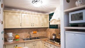 A kitchen with light-colored cabinets, a stove, a sink, and a microwave. - Rifugio con Terrazza Panoramica a Positano (Positano)