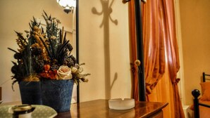 A room with a wooden dresser, a blue vase with dried flowers, and a bed with orange curtains. - Mainades Studio - Evrypyli Serene Escape in Andros (Andros)