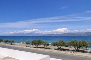 A coastal road with trees and a clear view of the sea and distant mountains. - Absolute Beachfront Bliss in Perigiali Korinthia (Corinth)