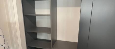Ein begehbarer Kleiderschrank mit mehreren Regalen und Schubladen, einer Tür und einem kleinen Tisch mit einer Vase.