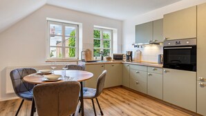 Une cuisine avec une table à manger, des chaises et une vue sur l’extérieur.