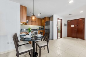 Eine moderne Küche mit Holzausstattung, einem Edelstahl-Kühlschrank und einem Essbereich mit Glastisch und Stühlen.