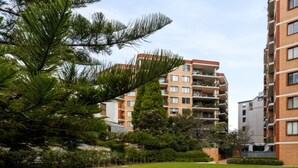 A residential building with multiple balconies, a grassy lawn, and a picnic table. - Stunning Downtown Retreat With City Views (Surry Hills)