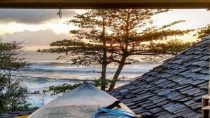 A view from a window overlooking the ocean with a surfboard and a blue rope on the windowsill. - Beach House NATUREZA (Itacare)