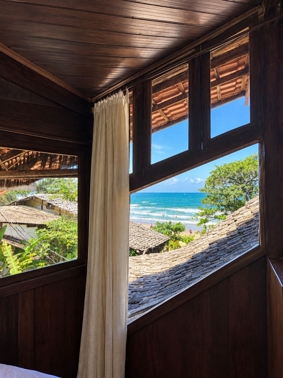 Ein Zimmer mit großem Fenster und Blick auf Strand und Meer.