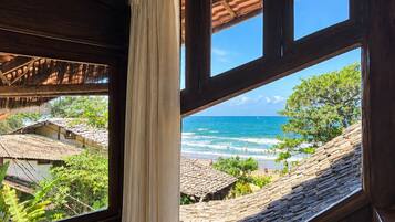 Ein Zimmer mit großem Fenster und Blick auf Strand und Meer.