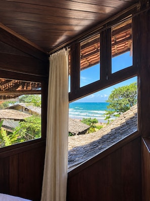 A room with a large window overlooking a beach and ocean. - Beach House NATUREZA (Itacare)