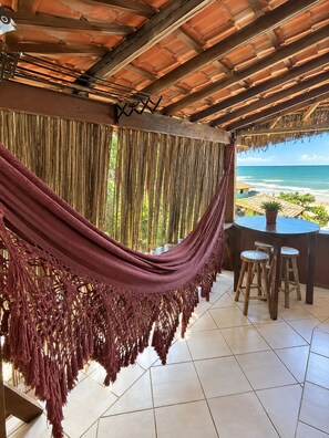 A room with a view of the ocean, a hammock, and a table with stools. - Beach House NATUREZA (Itacare)