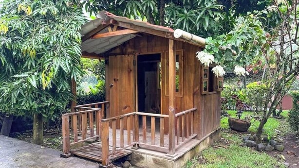 Une petite cabane en bois avec une véranda et une porte donnant sur l’intérieur.