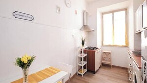 A compact kitchen with white cabinets, a gas stove, and a window providing natural light. - [Centocelle - Happy Domus] Oasis of the Sun (Roma)