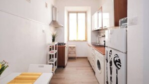 A compact kitchen with white cabinets, a built-in oven, and a washing machine. - [Centocelle - Happy Domus] Oasis of the Sun (Roma)