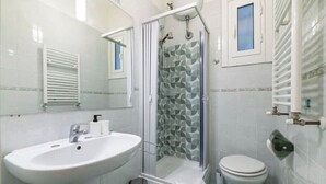 Et badeværelse med vask, toilet, brusebad og bidét.