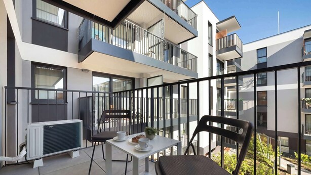 Eine moderne Wohnung mit Balkon, Tisch und Stühlen sowie einer Heizung.