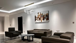 A modern living room with a sofa set, a coffee table, and a painting on the wall.
