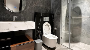 A modern bathroom with a marble vanity, a toilet, and a glass-enclosed shower.