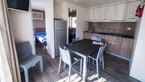 Una cucina compatta con zona pranzo, frigorifero integrato e mobili in legno.
