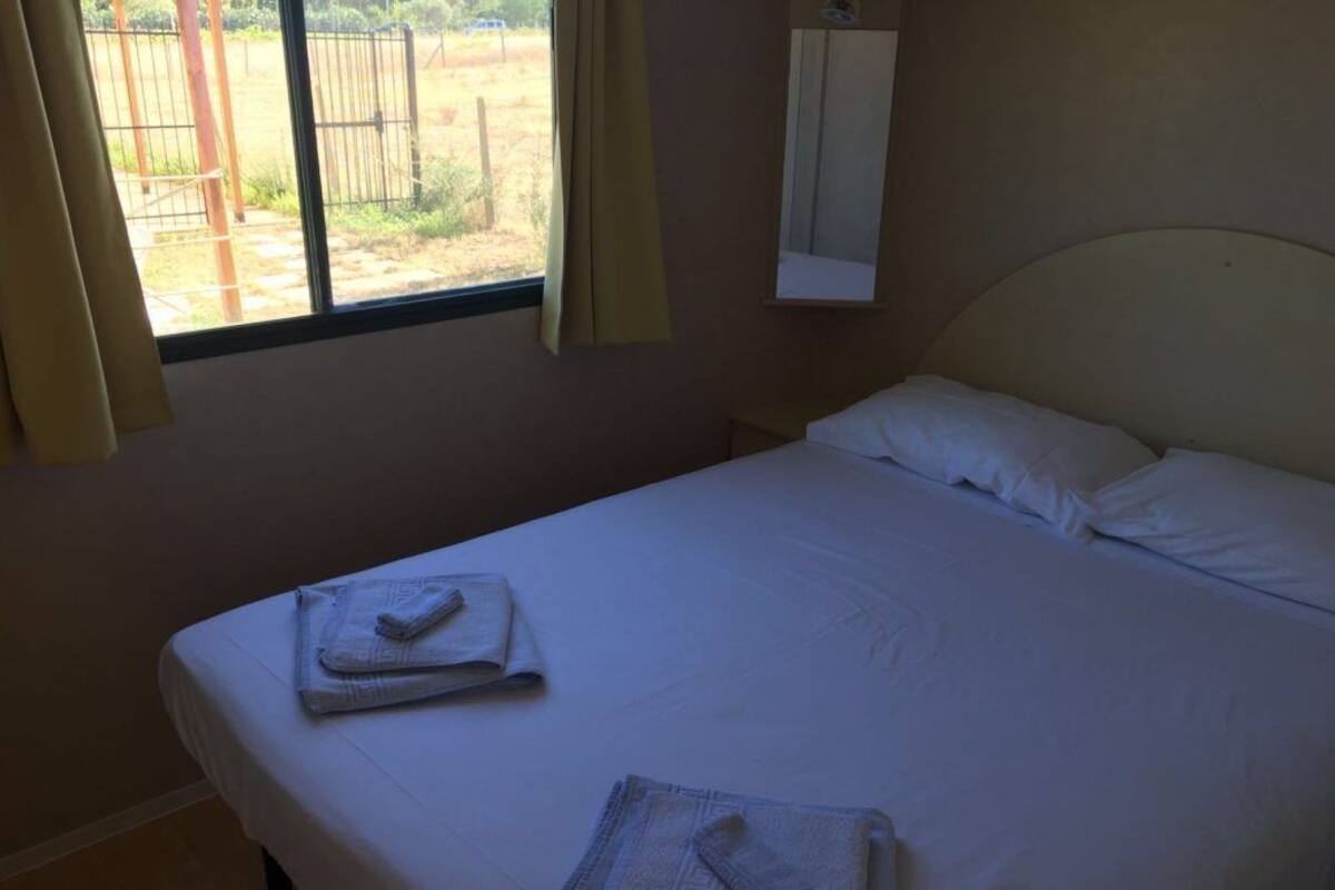 A single bed with white linens and two folded towels.
